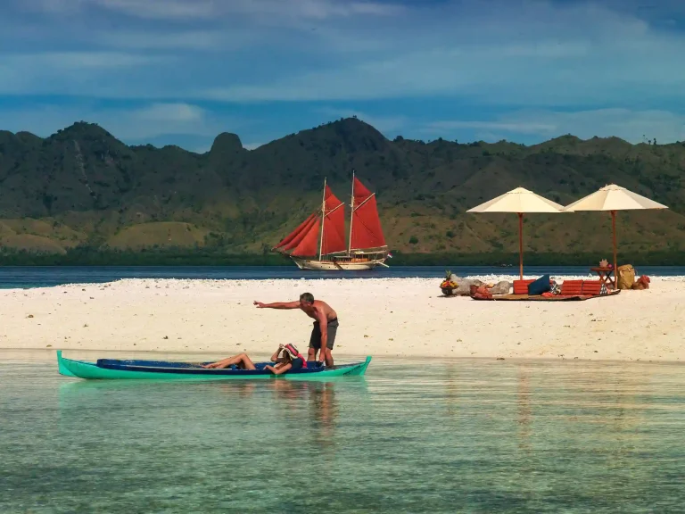 Phinisi and outrigger canoe off a Komodo beach
