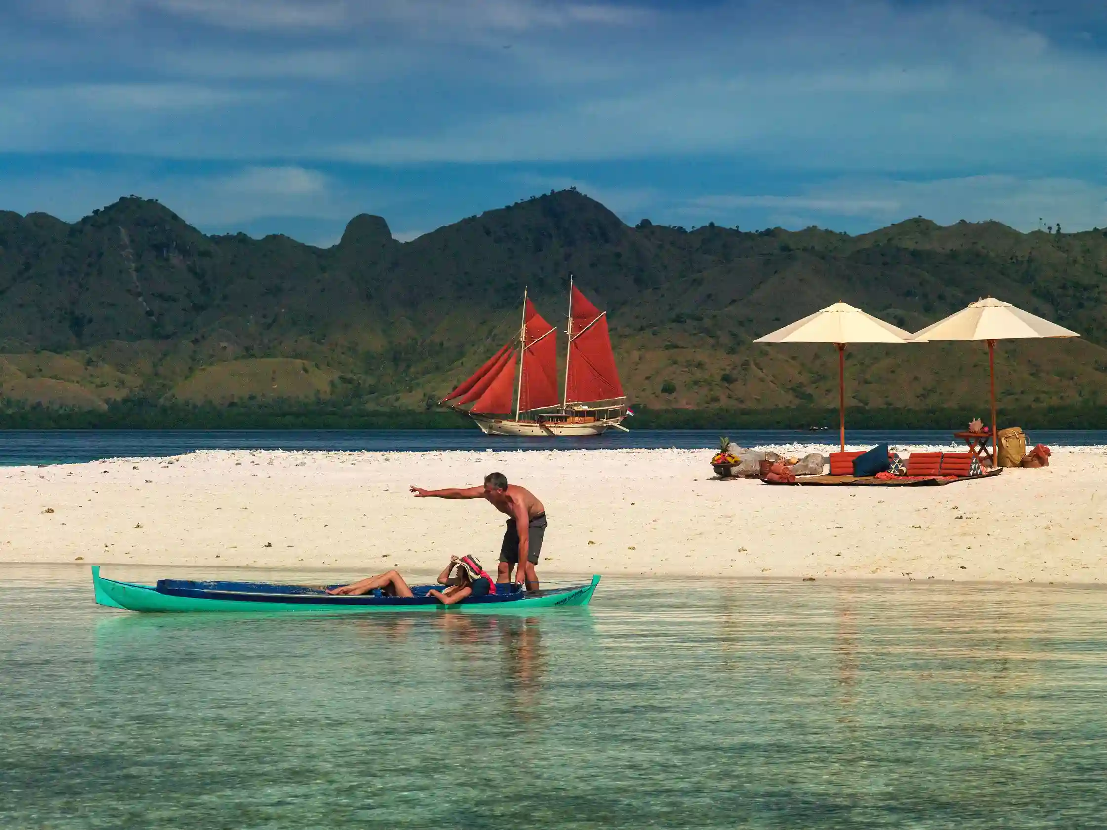 Phinisi and outrigger canoe off a Komodo beach