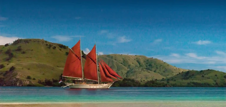 Phinisi under red sails in Komodo National Park